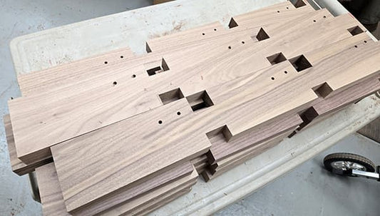 stack of notched and drilled walnut pieces which will eventually become scroll heads for Folkcraft dulcimers